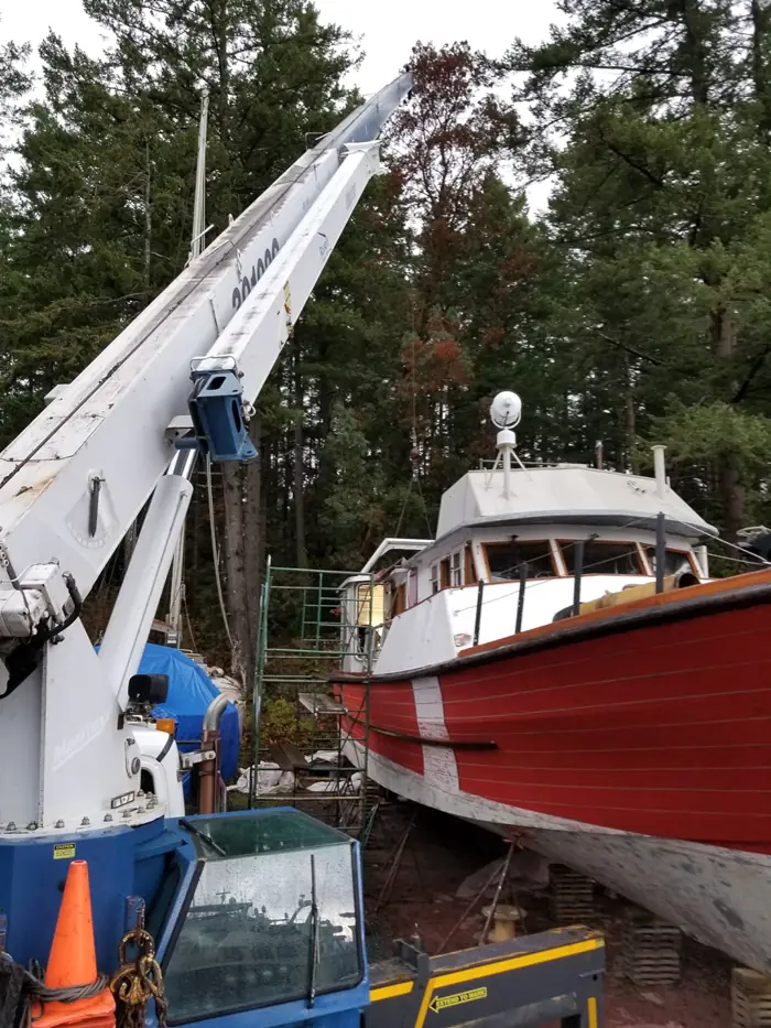 Crane beside a red wooden boat in dry dock