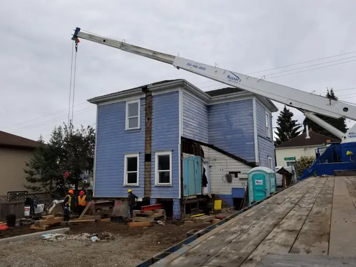 Crane lifting a blue house section into place