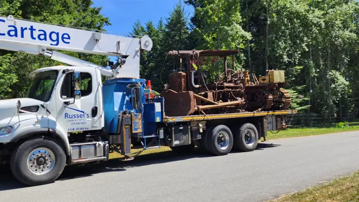 Boom truck hauling equipment on a flat deck