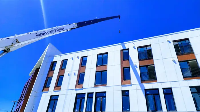 Crane lifting materials beside a new multi-storey building