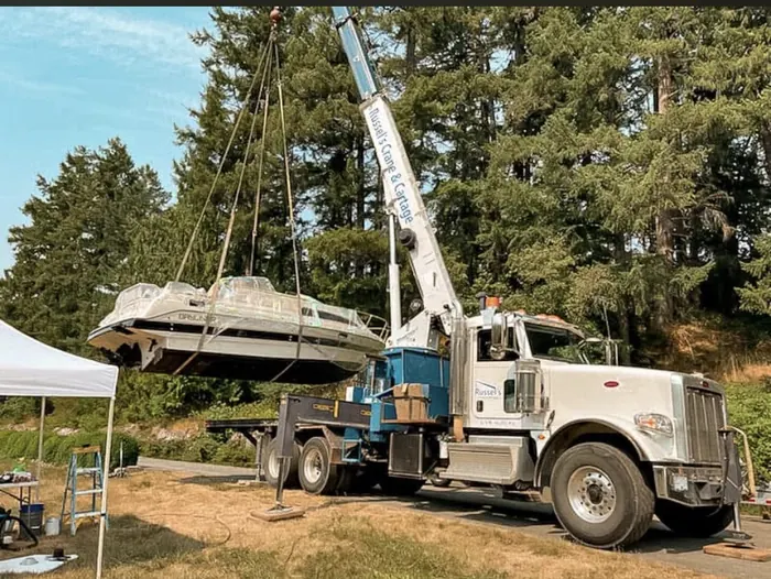 Russel's crane truck lifting a boat on a grassy site