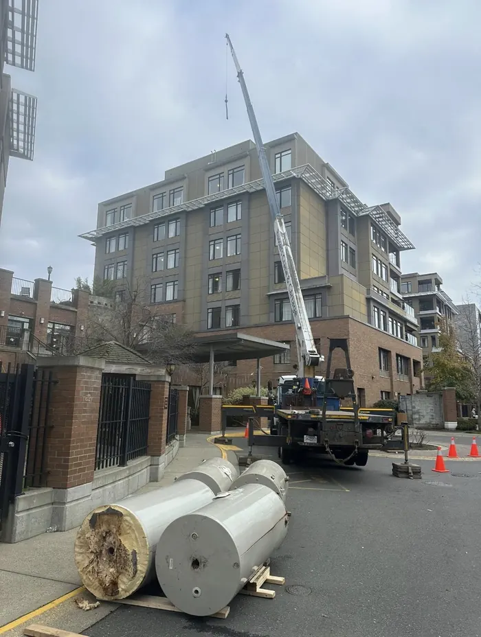 Crane boom extended at a condo building with large tanks on the ground