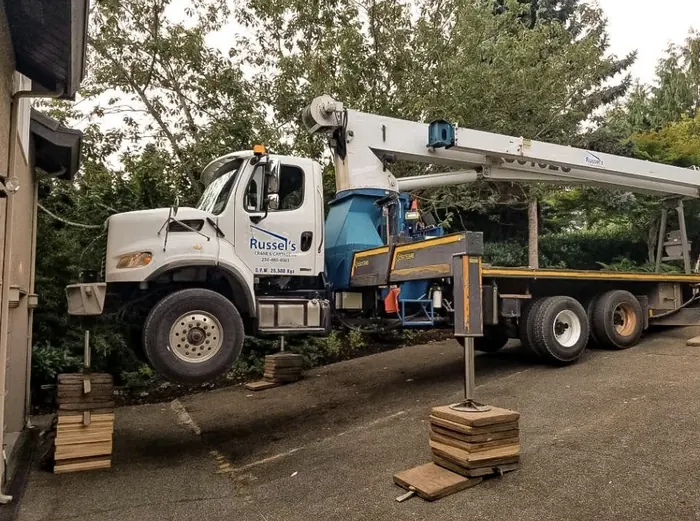 Crane truck on outriggers with cribbing in a residential driveway