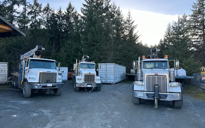 Three Russel's Crane & Cartage boom trucks lined up in the yard
